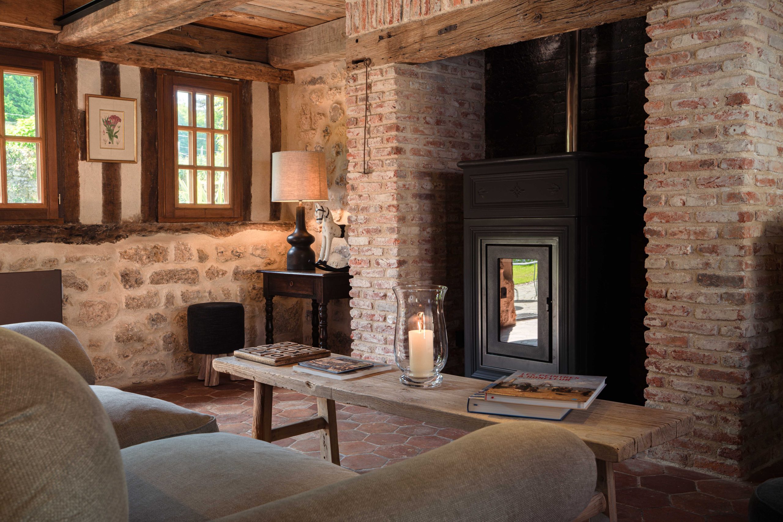 sala de estar com parede de tijolo e fogão a lenha na grande forja do auberge de la source - cottage honfleur